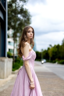a woman in a pink dress standing on a sidewalk