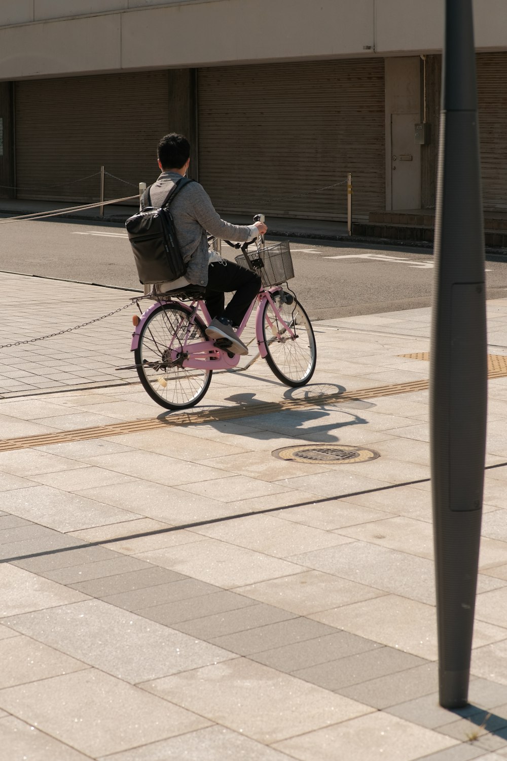 a man riding a pink bike down a street