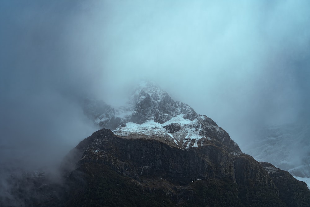 a very tall mountain covered in snow and clouds