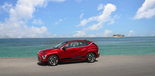 A bright, sunny coastal road in Mayotte with a parked SUV near the lagoon.