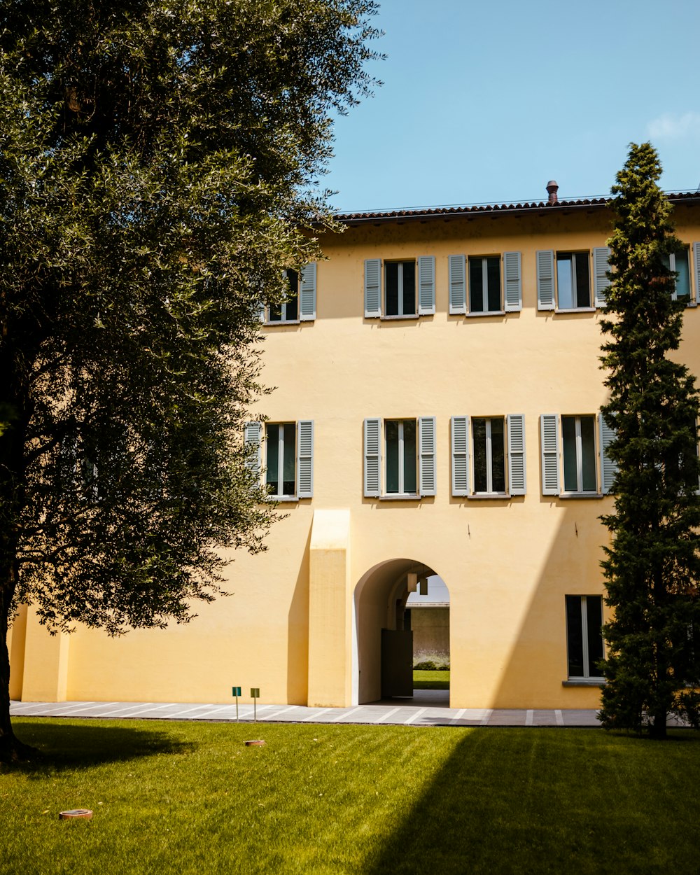 a large yellow building with two trees in front of it