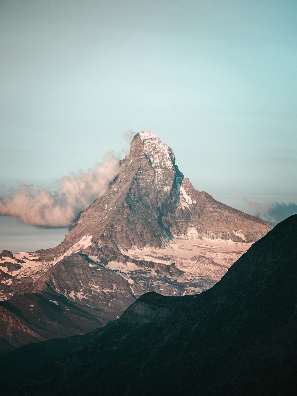 ein schneebedeckter Berg mit Wolken am Himmel