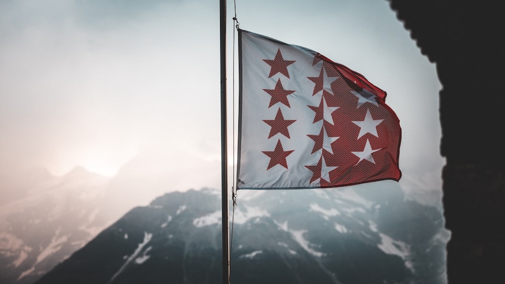 a flag flying in the wind with mountains in the background