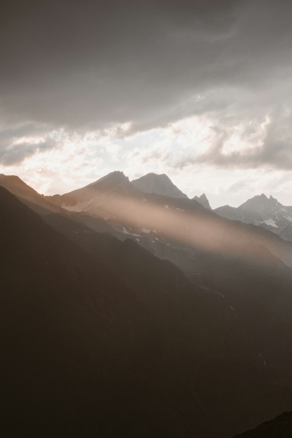 the sun is shining through the clouds in the mountains