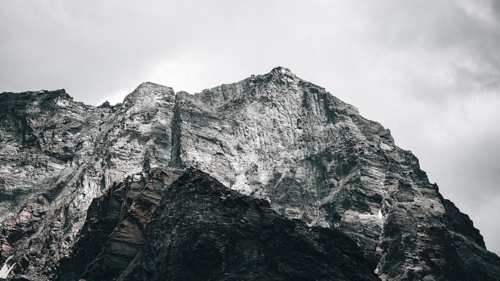 a very tall mountain covered in snow under a cloudy sky