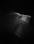 An open book held by someone's hands is illuminated by a focused light source in an otherwise dark environment. One page features a heading 'Creating Consistent Content That Readers Love' and some text below it.