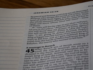 A close-up view of an open Bible page, showing text from the book of Jeremiah. The text appears in a column format with chapter and verse numbers visible. The page has a slightly blurred focus, with emphasis on specific verses of a religious text.