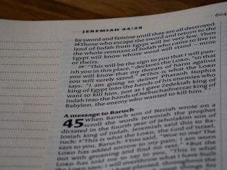 A close-up view of an open Bible page, showing text from the book of Jeremiah. The text appears in a column format with chapter and verse numbers visible. The page has a slightly blurred focus, with emphasis on specific verses of a religious text.