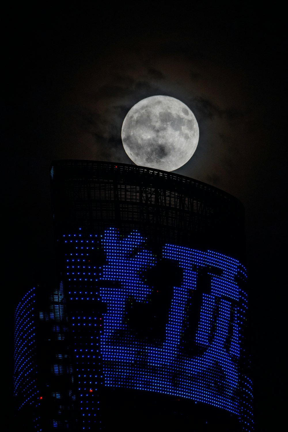 a full moon is seen above a building