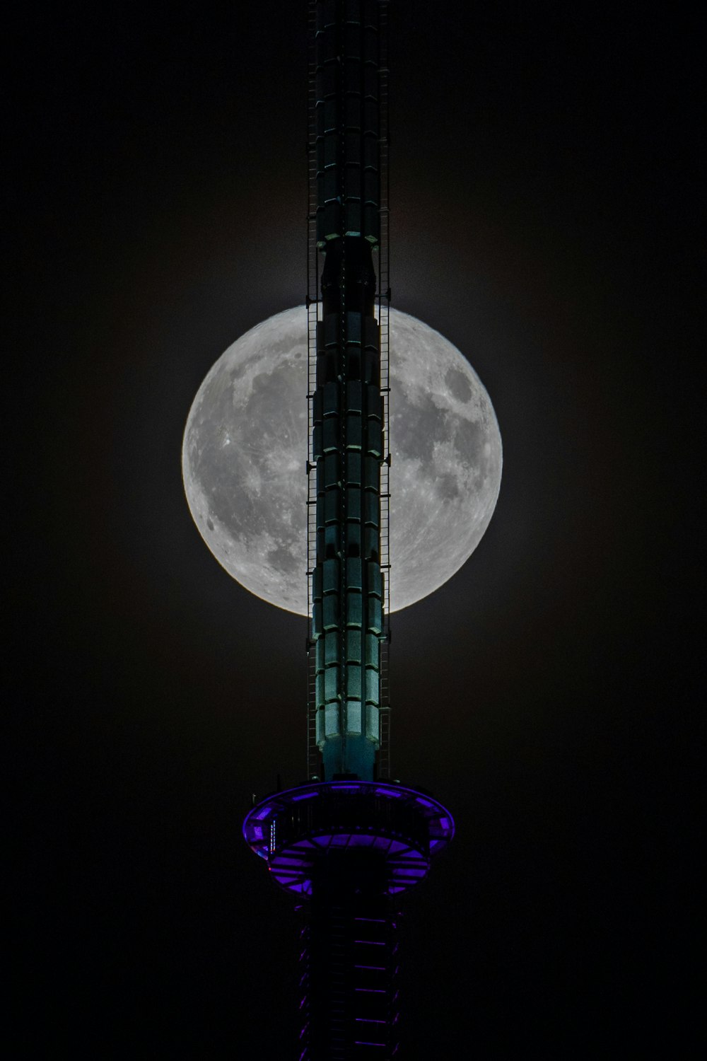 a tall tower with a very large moon in the background