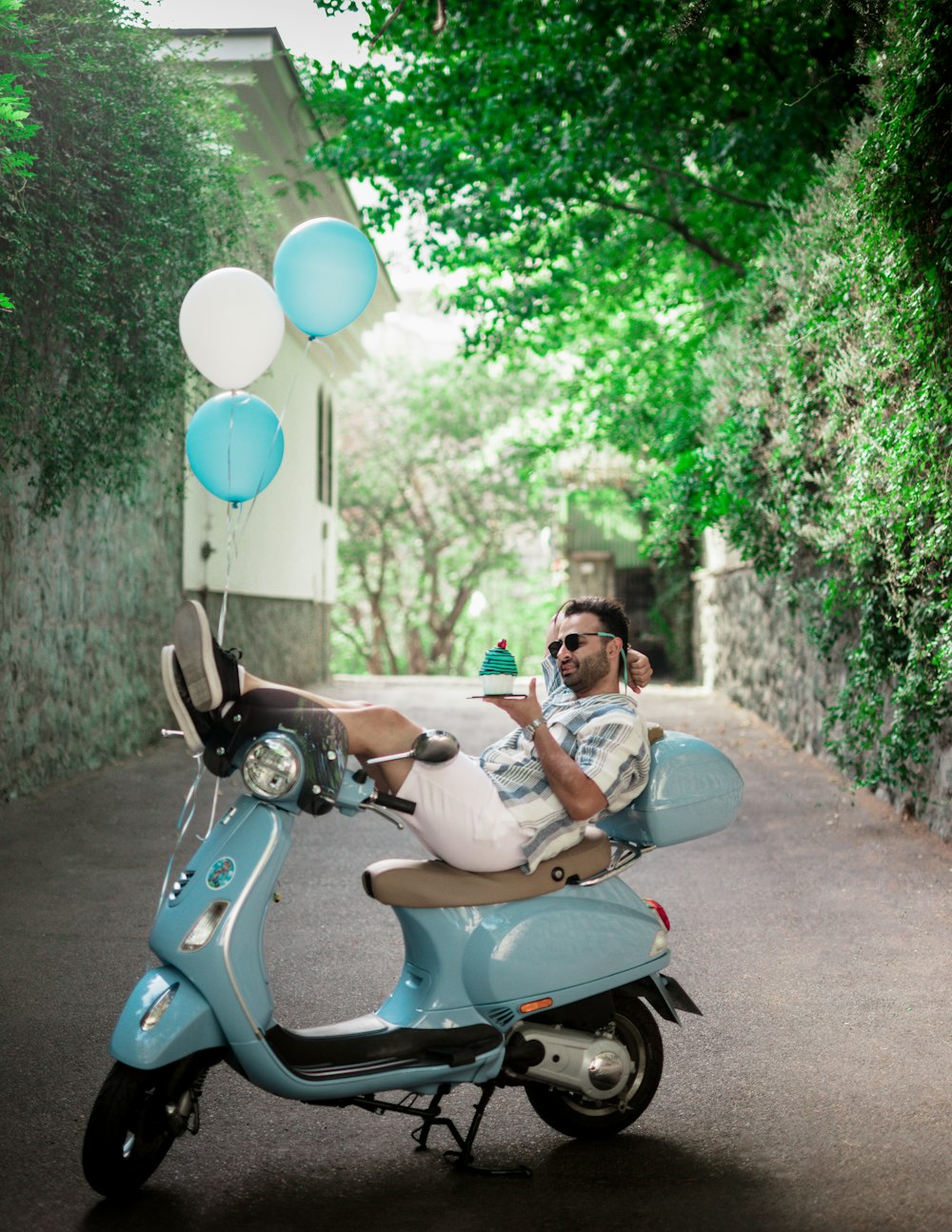 um homem está sentado em uma scooter com balões