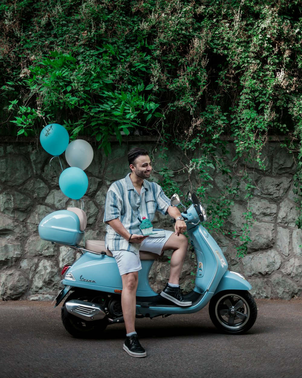 a man is sitting on a scooter with balloons