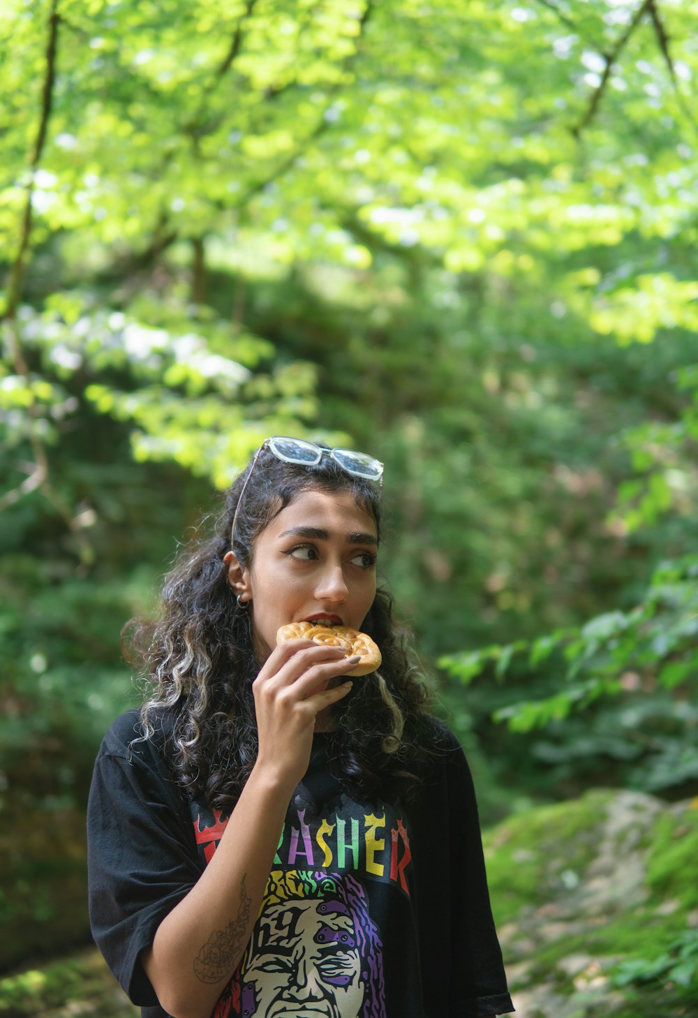 a girl eating a donut in the woods