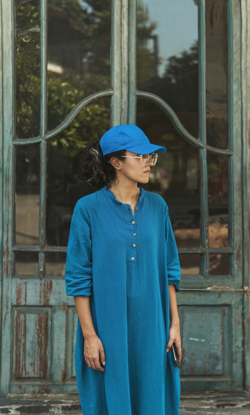 a woman standing in front of a door wearing a blue hat
