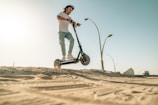 a man riding a scooter on top of a sandy beach