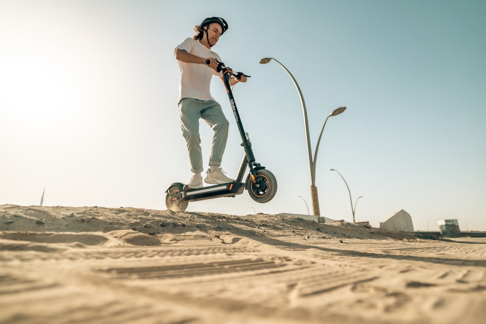 a man riding a scooter on top of a sandy beach