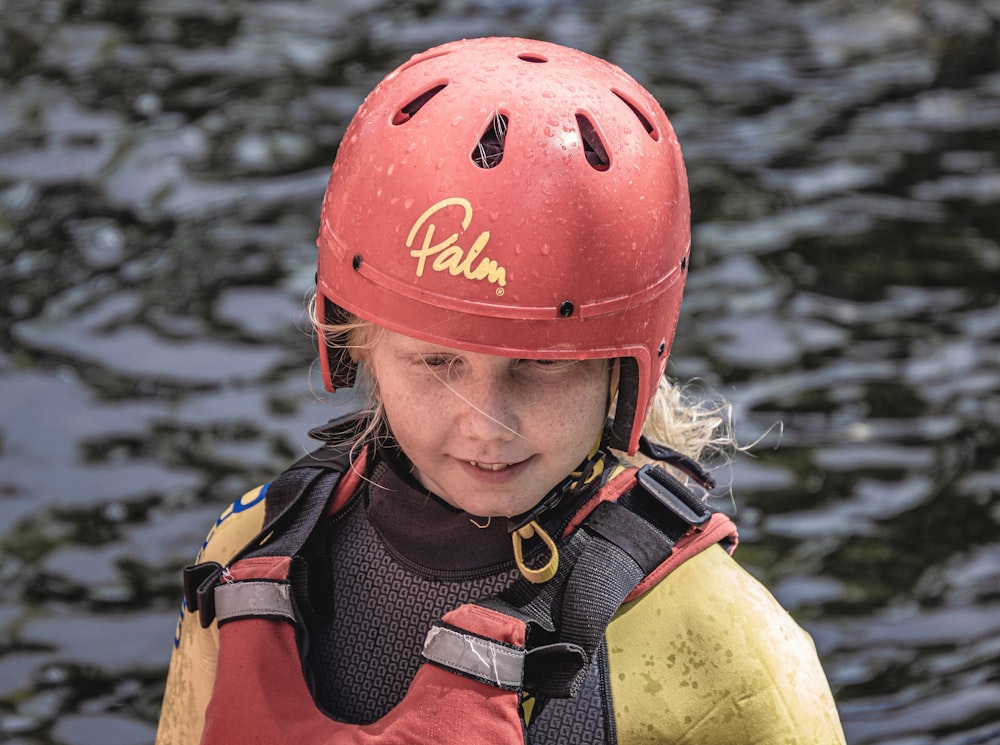 a young girl wearing a life jacket and a helmet