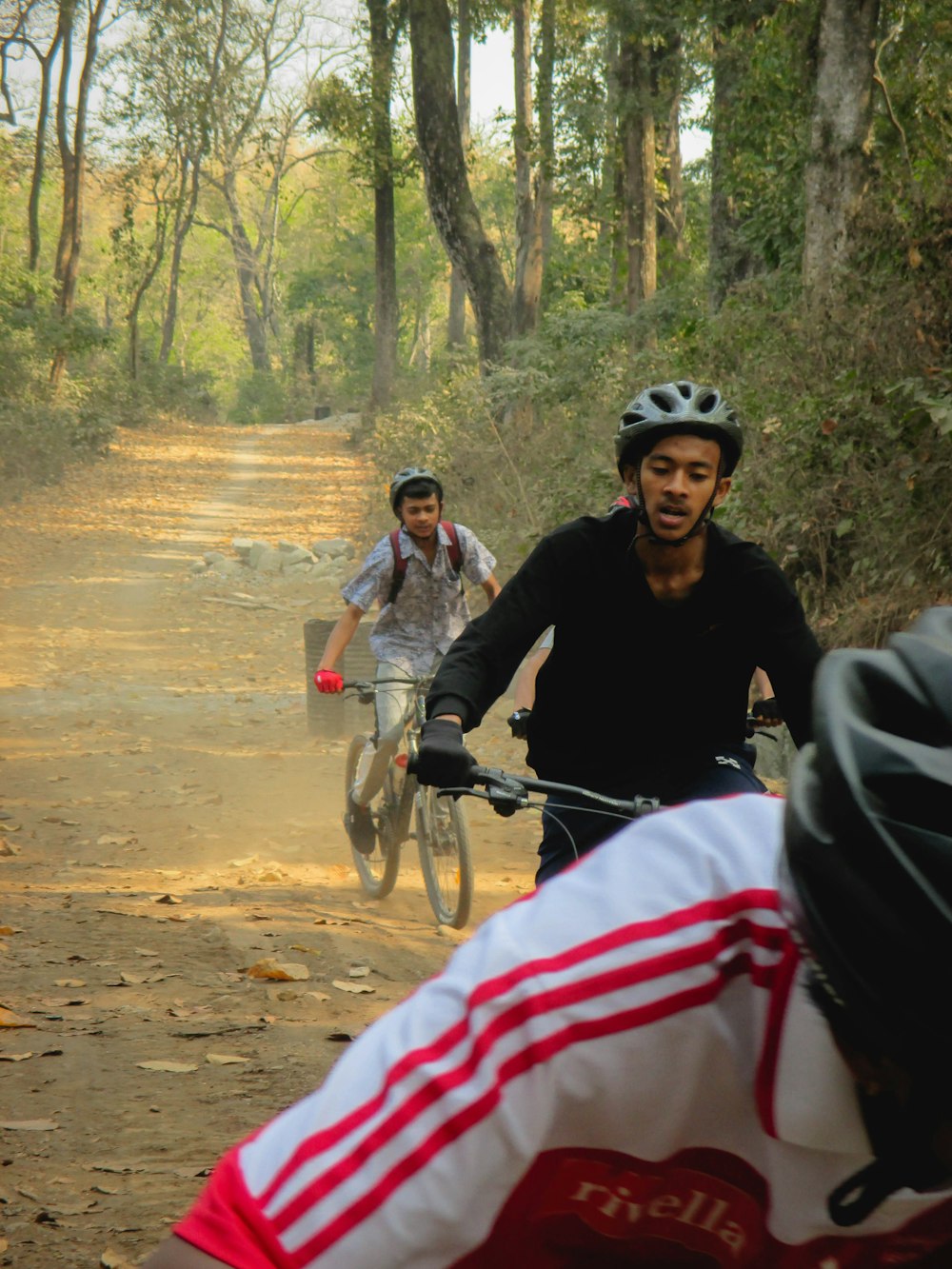 a couple of men riding bikes down a dirt road