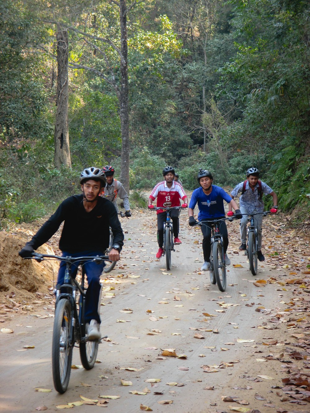 a group of people riding bikes down a dirt road