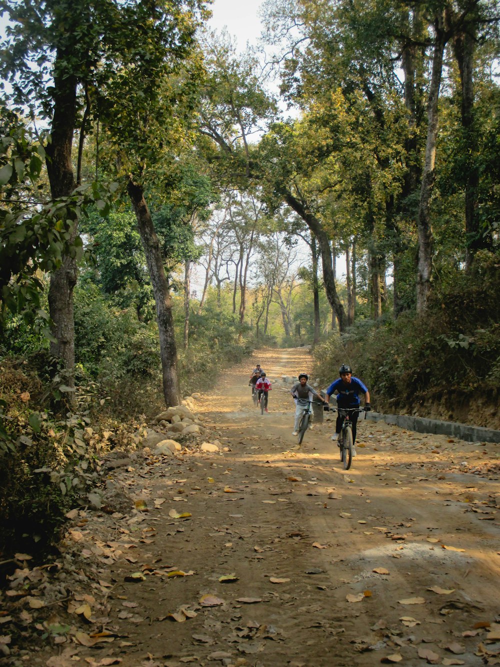 a group of people riding bikes down a dirt road