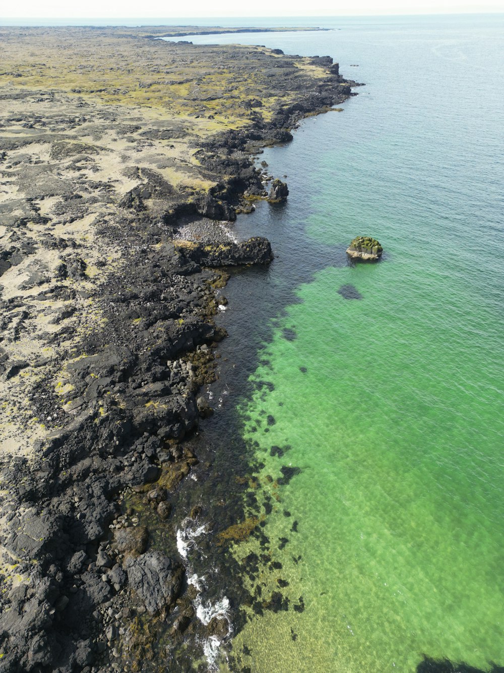 eine Luftaufnahme eines Gewässers mit einer kleinen Insel in der Mitte des