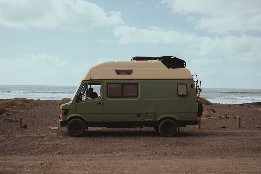 a green van parked on the beach next to the ocean