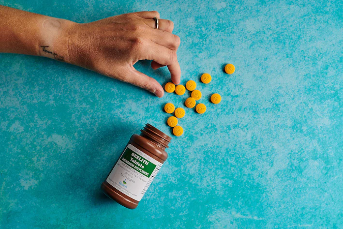 Close-up of a hand picking up a prescription medicine bottle from a neatly organized shelf.