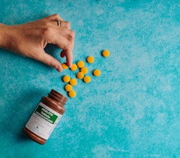 Close-up of a hand picking up a prescription medicine box from a pharmacy shelf.