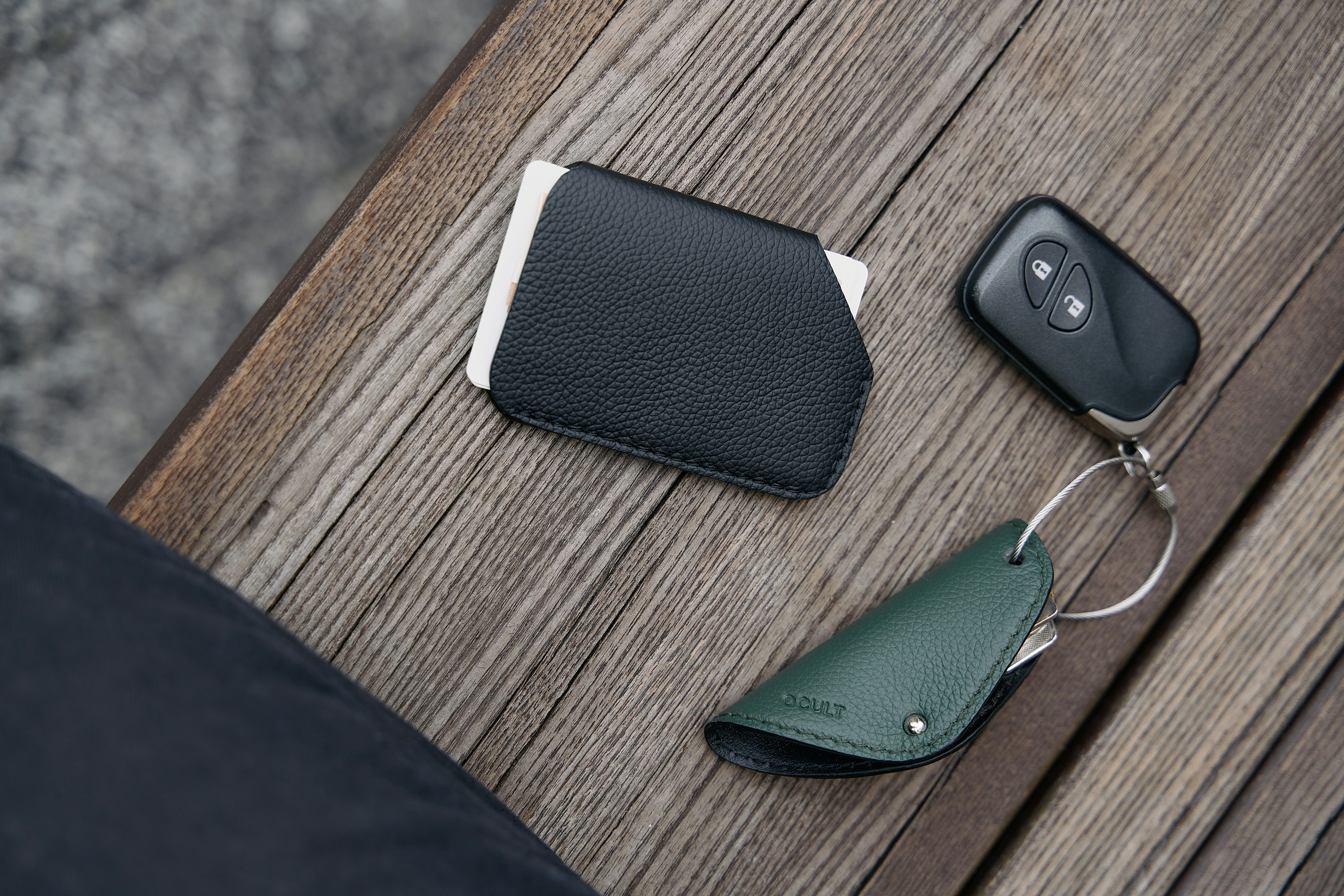 a cell phone, wallet, and keychain sitting on a table