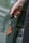 A hand holding a car key fob attached to a brown leather key holder in front of a blurred background.