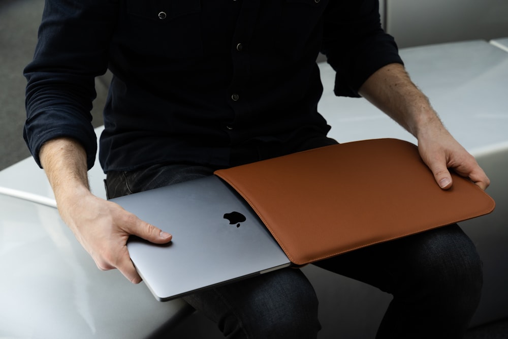 a man sitting on a chair holding a laptop