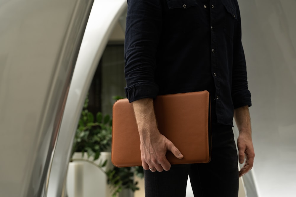Un hombre sosteniendo un maletín marrón en la mano