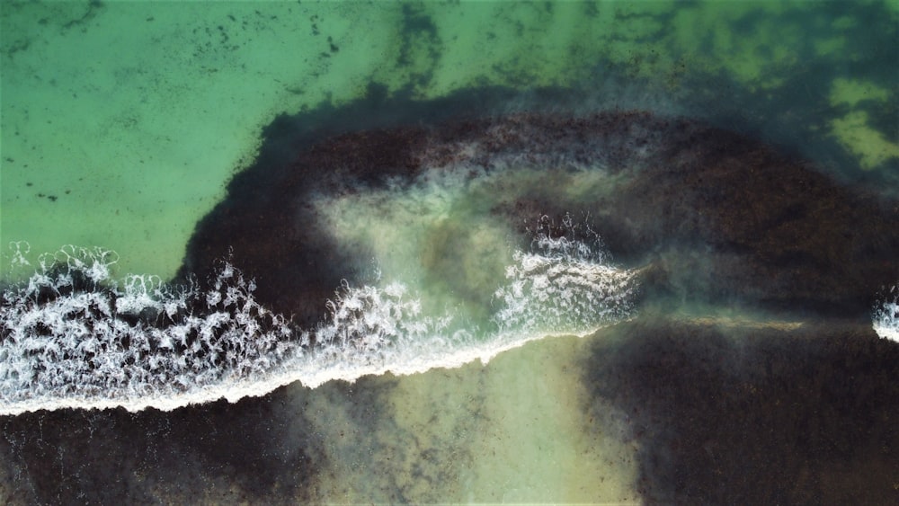 an aerial view of the ocean with waves crashing on the shore