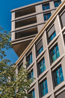 a tall building with lots of windows next to a tree