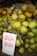 Close-up photo of fresh young coconuts with green husks, piled up at a market stall.