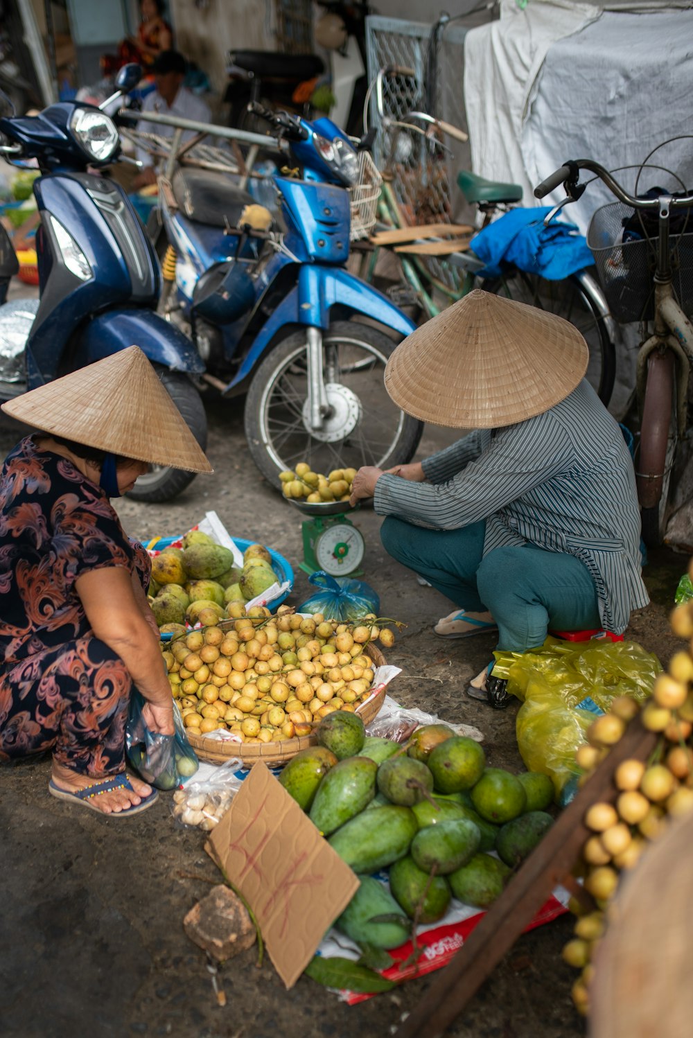 a woman kneeling down next to a pile of fruit