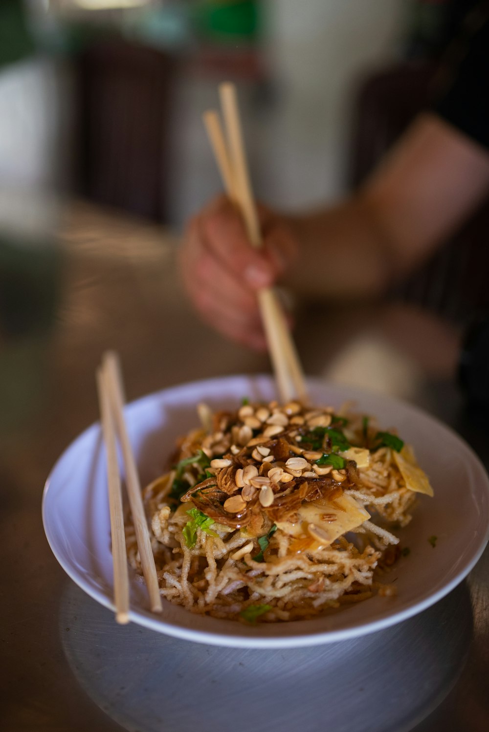 a bowl of noodles with chopsticks on a table