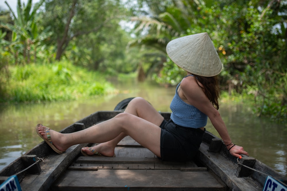 a woman in a straw hat is sitting on a boat
