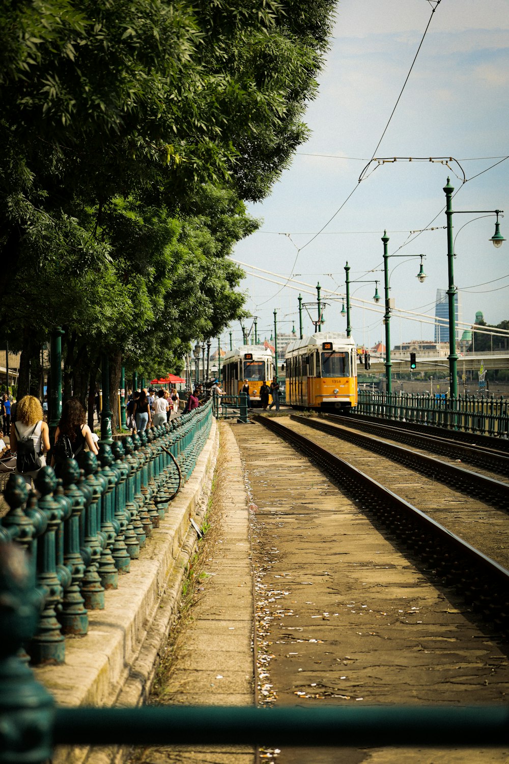 a yellow train traveling down train tracks next to a forest