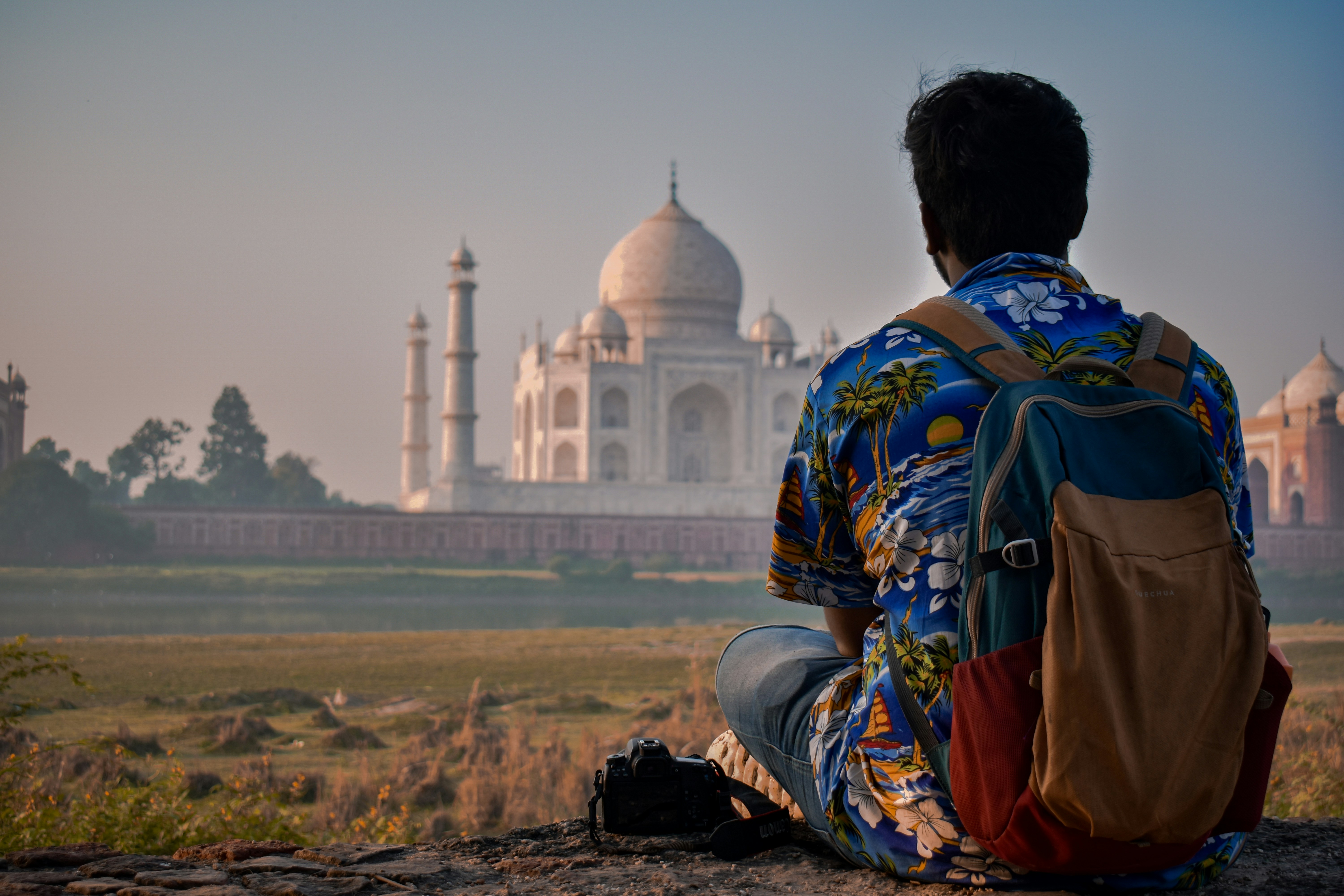 A man sitting on a rock looking at a building
