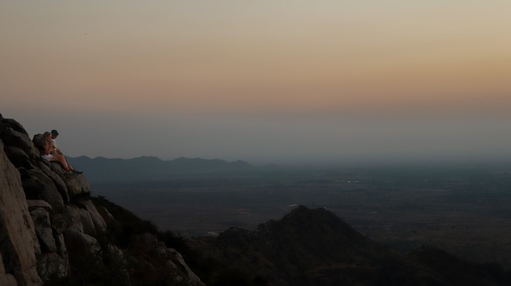 a couple of people sitting on top of a mountain