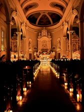 A softly lit church interior with dusty blue floral arrangements and warm candlelight.