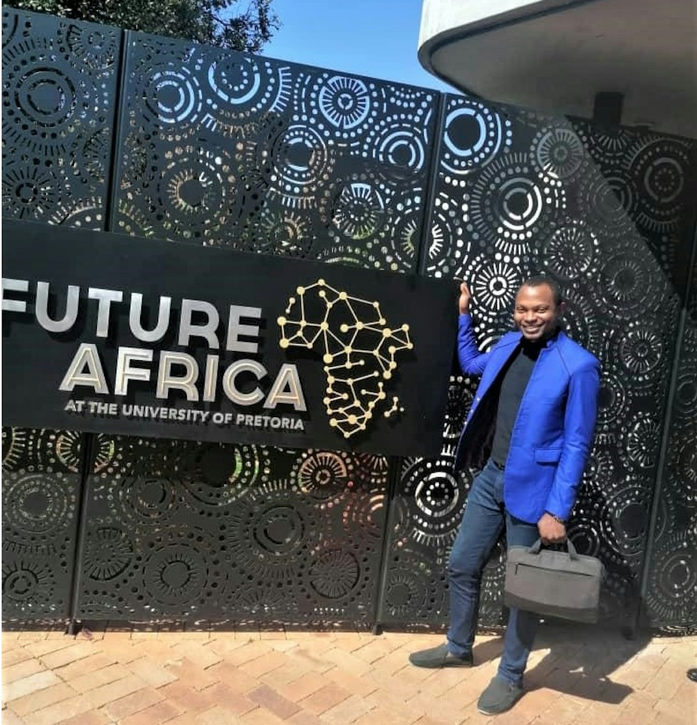 未来アフリカと書かれた看板の前に立つ男