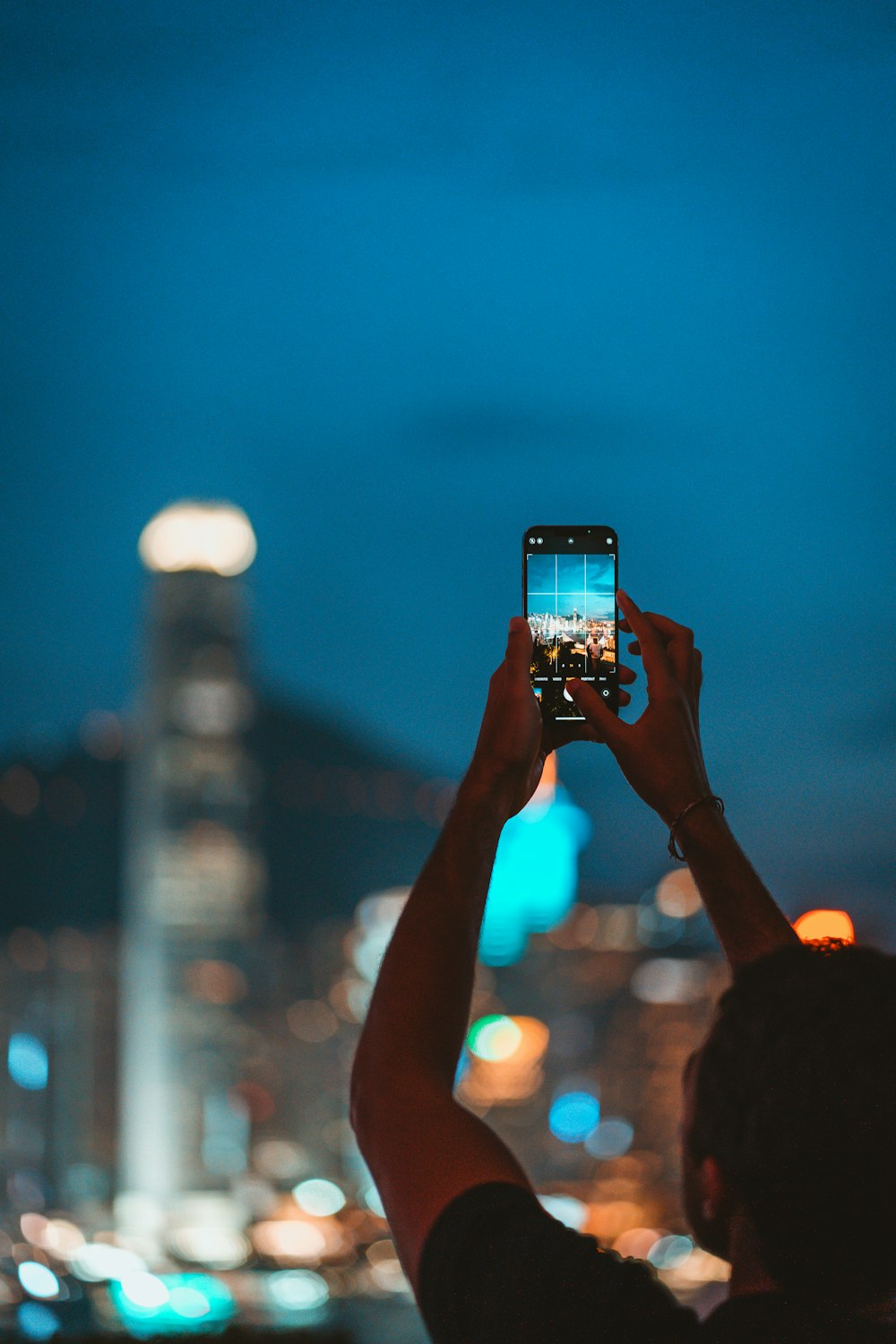 uma pessoa tirando uma foto de uma cidade à noite