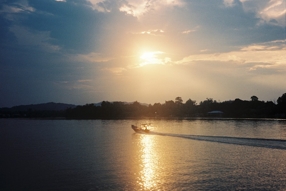 a boat traveling across a body of water under a cloudy sky