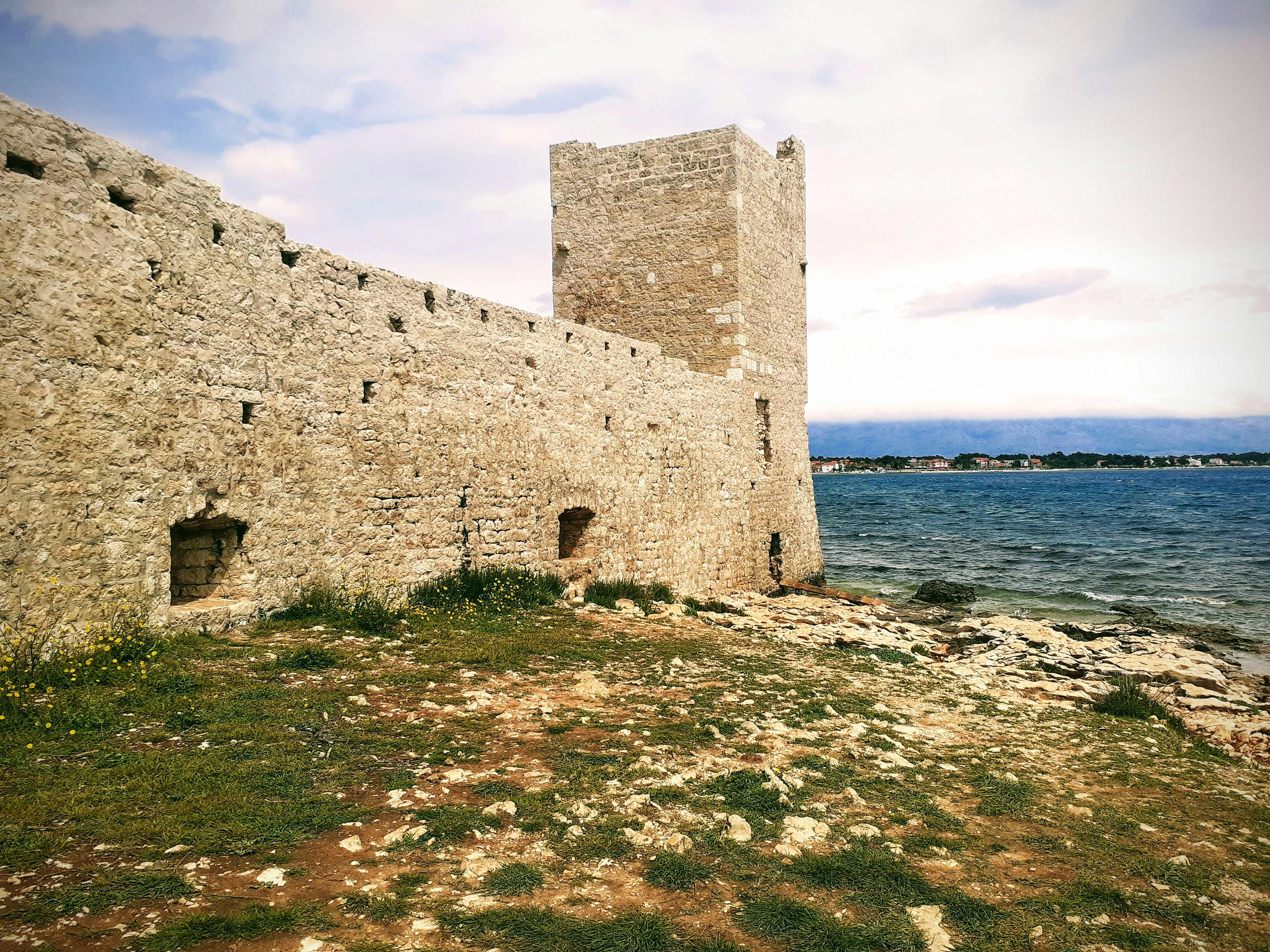 A stone castle sitting next to a body of water