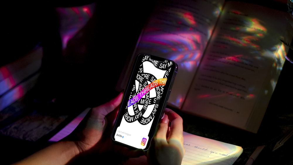 a person holding a cell phone in front of a book