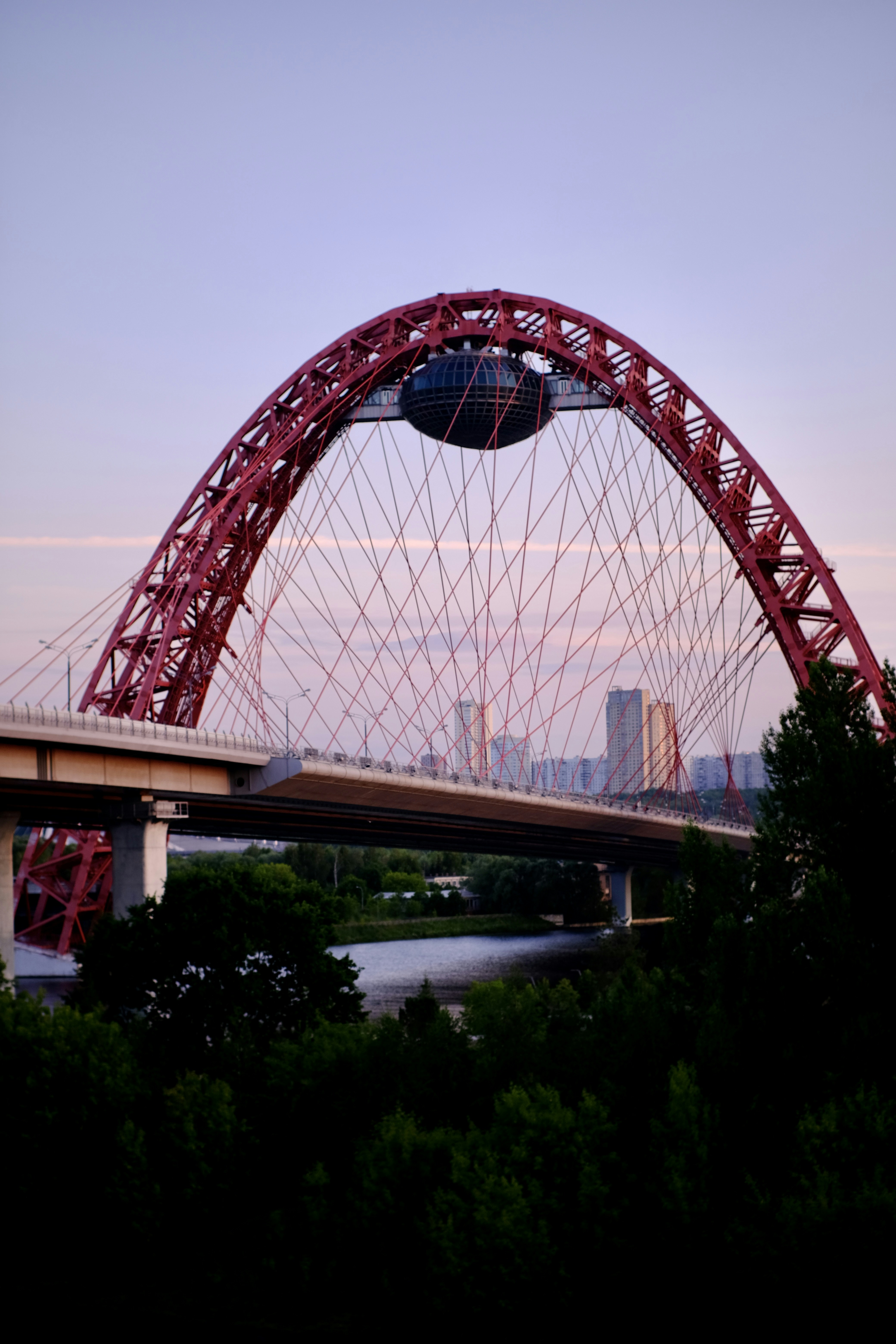 a large red bridge over a river with a city in the background