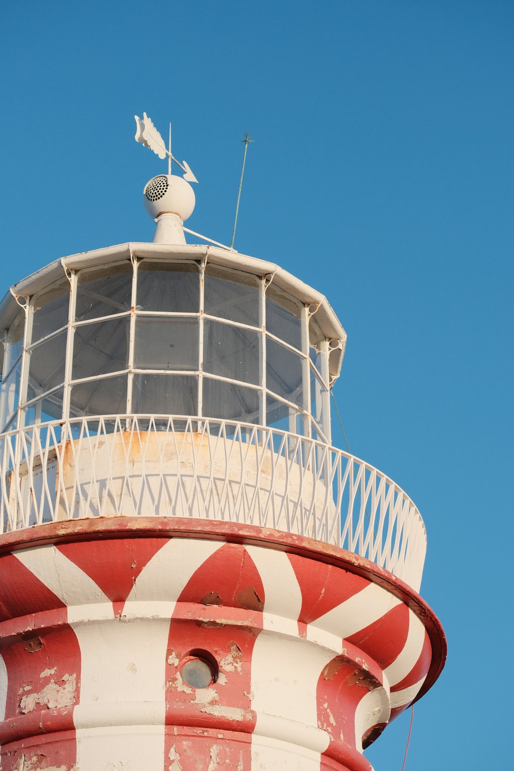 a red and white lighthouse with a bird on top