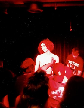 Artist performing live on stage with red lighting highlighting the energy.